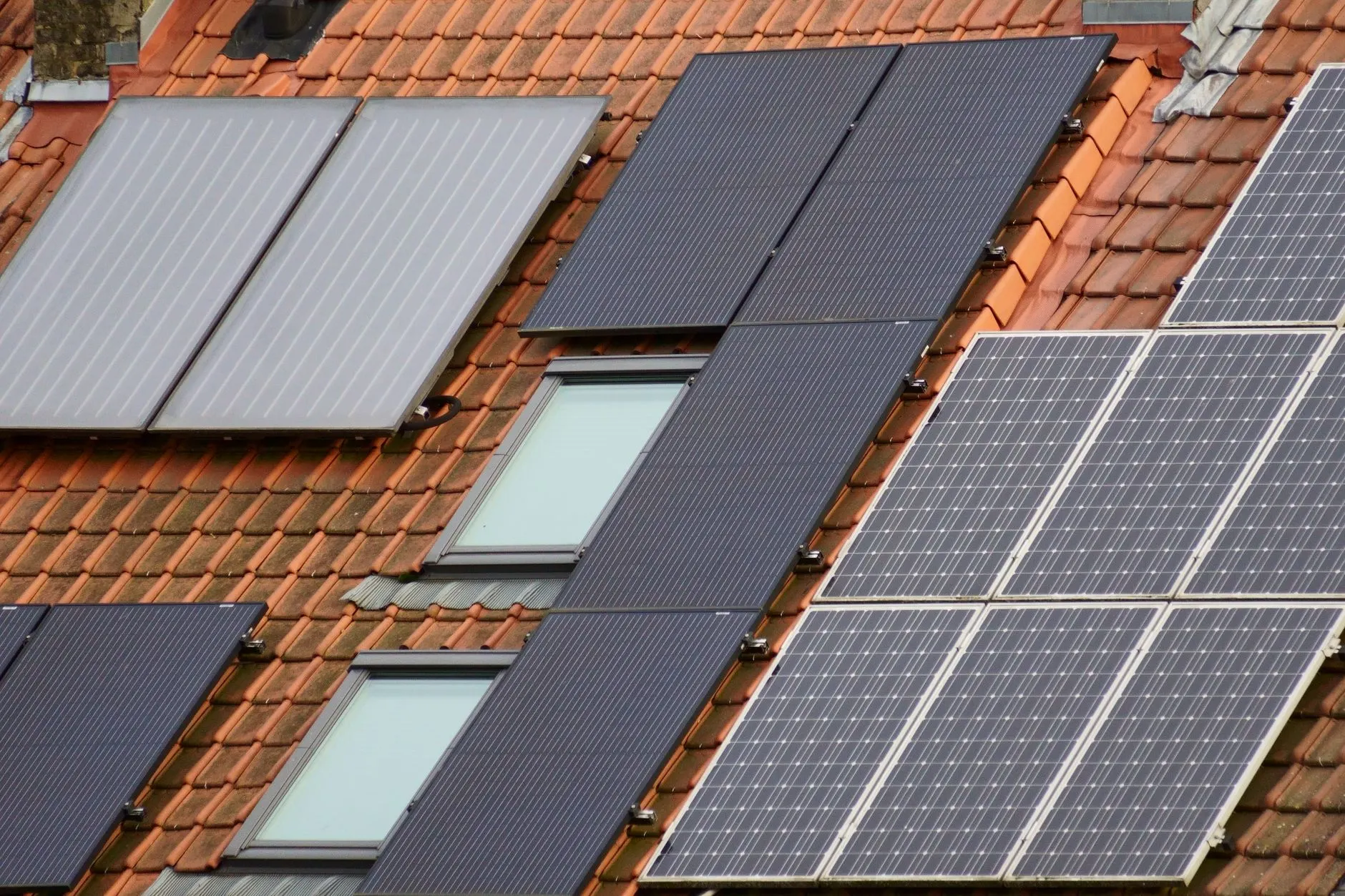 Steildach mit roten Pfannen, Dachfenstern, PV-Modulen und Solarthermie-Kollektoren