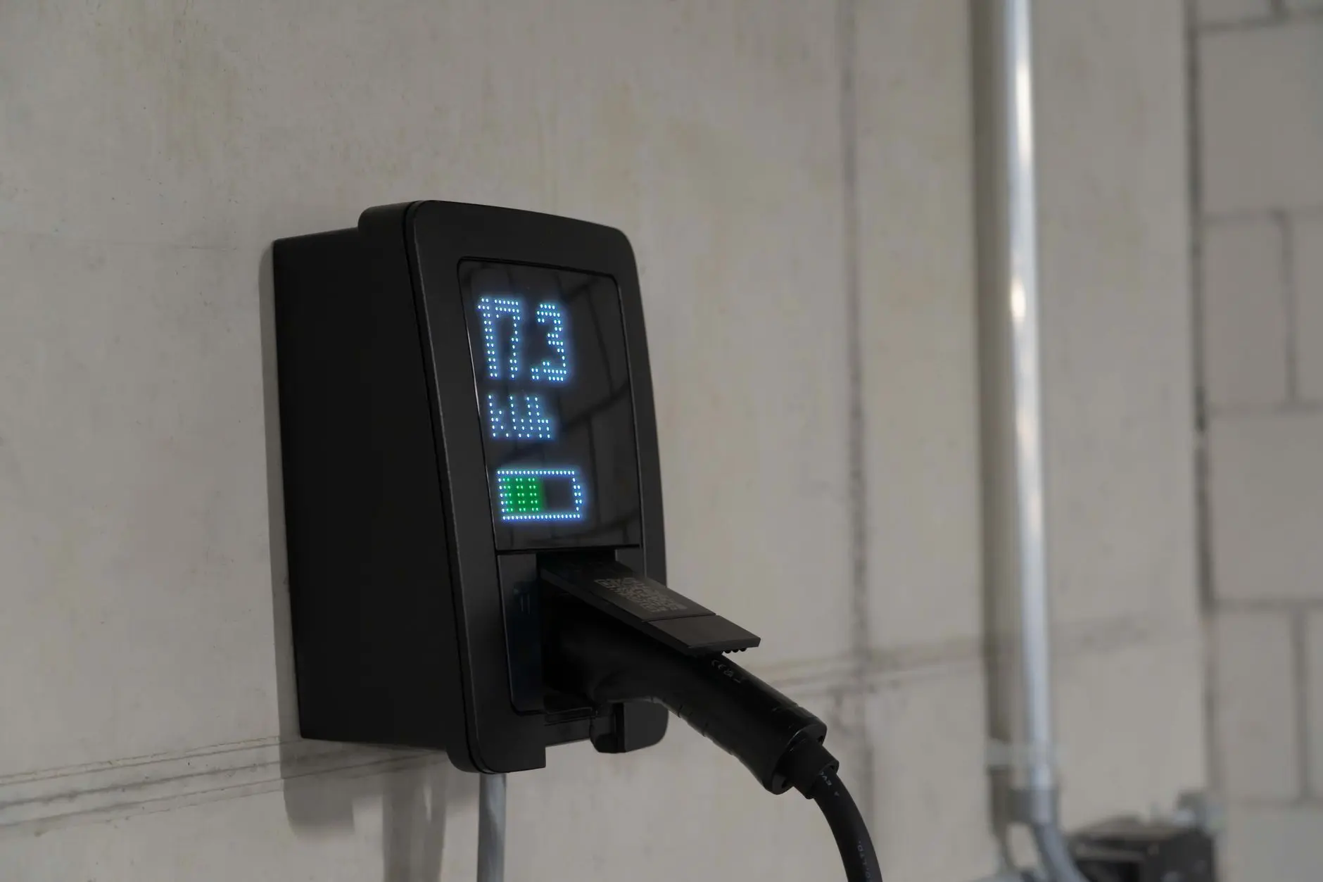 Wallbox mit kWh-Anzeige an einer Betonwand