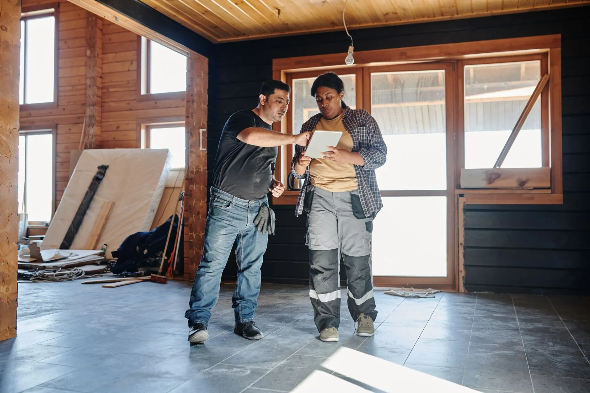 Zwei Handwerker besprechen etwas auf einem Tablet im Holzrohbau