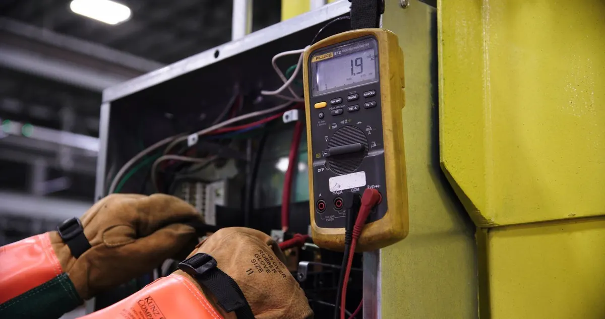Elektriker misst mit dem Multimeter an einem geöffneten Schaltschrank - DGUV V3 Prüfung in der Praxis