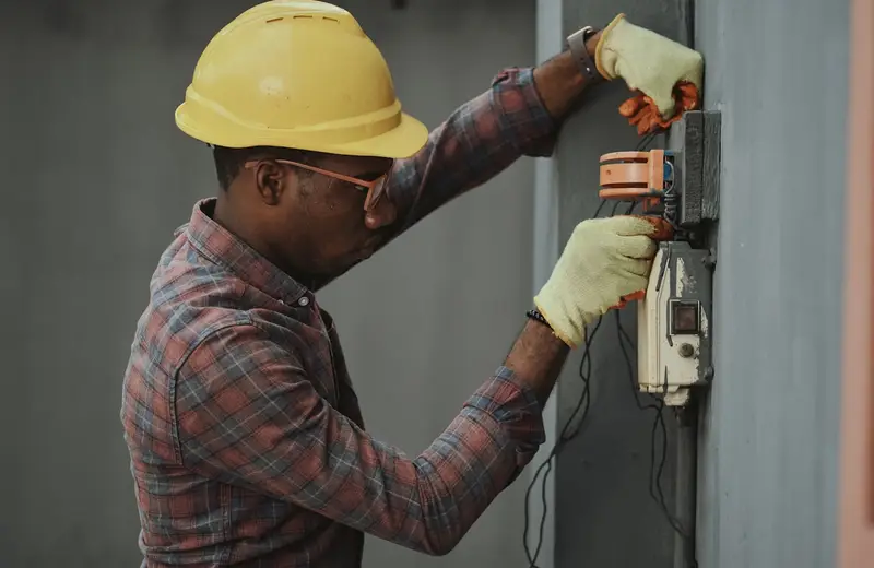 Elektriker mit Schutzhelm bei der Installation auf der Baustelle