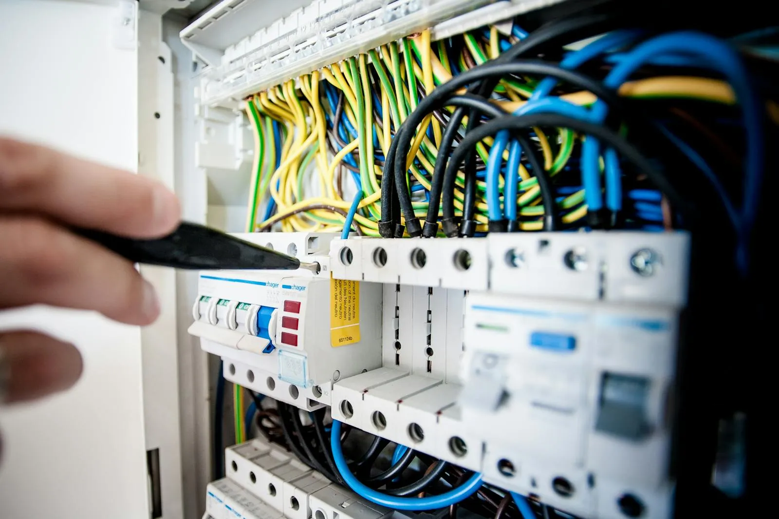 Elektriker arbeitet an einem Zählerschrank mit farbigen Kabeln